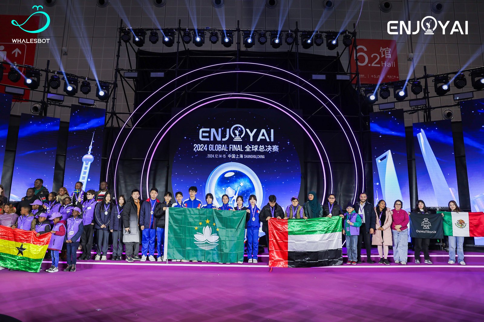 A student team on stage holding the UAE flag at the ENJOY AI 2024 Global Final