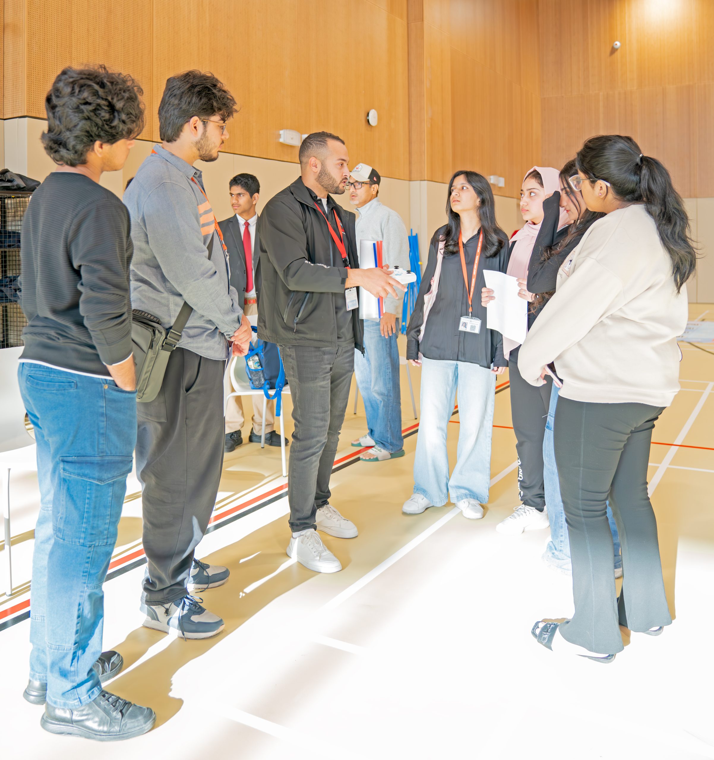 A coach briefing a group of student team members holding their project notes