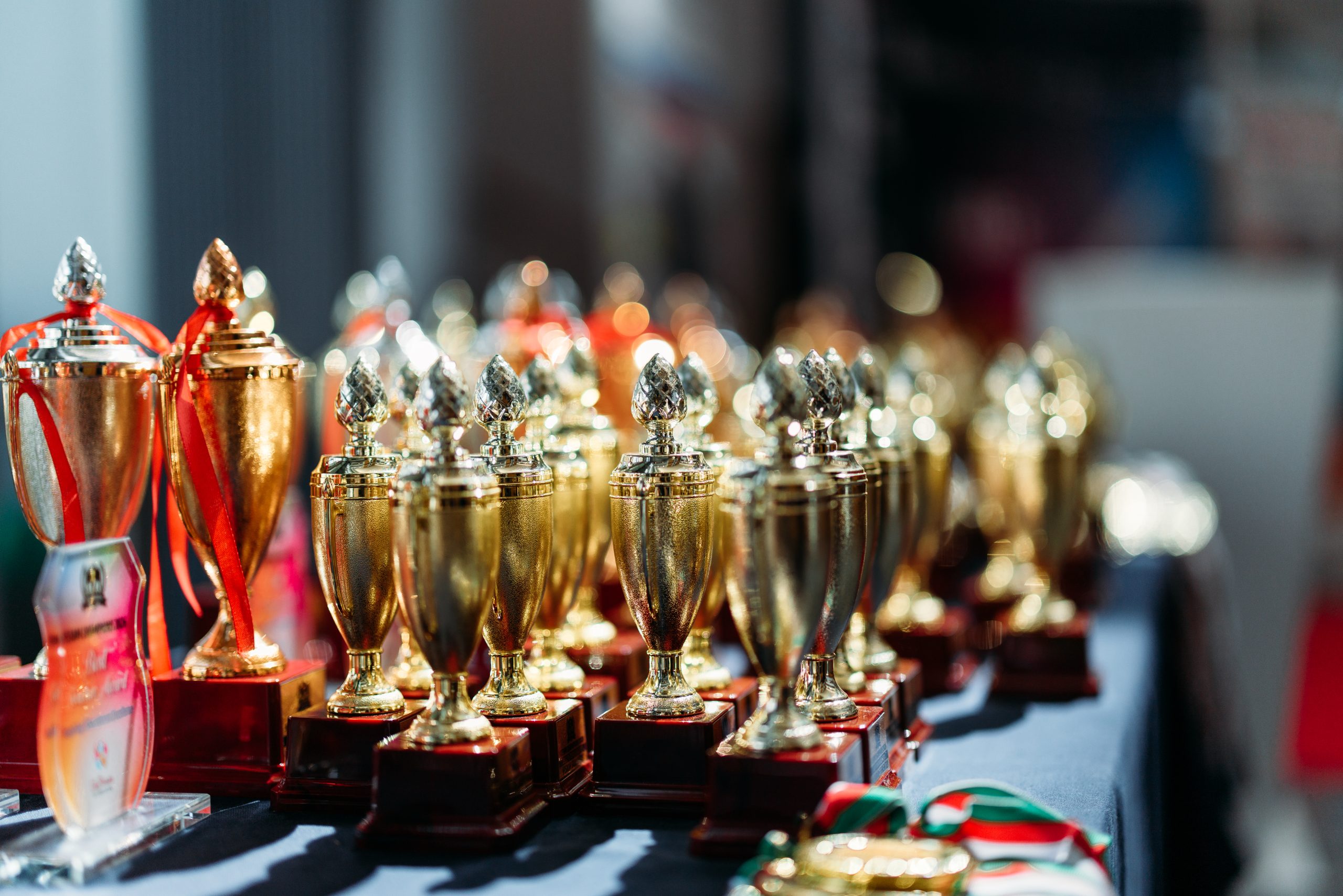 Rows of gold trophies and cups displayed on an awards table