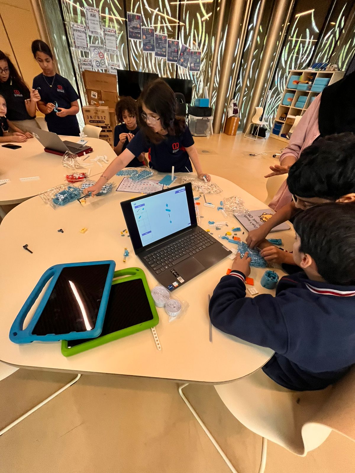 Students assembling a build while block coding on a laptop during a project-based design lesson