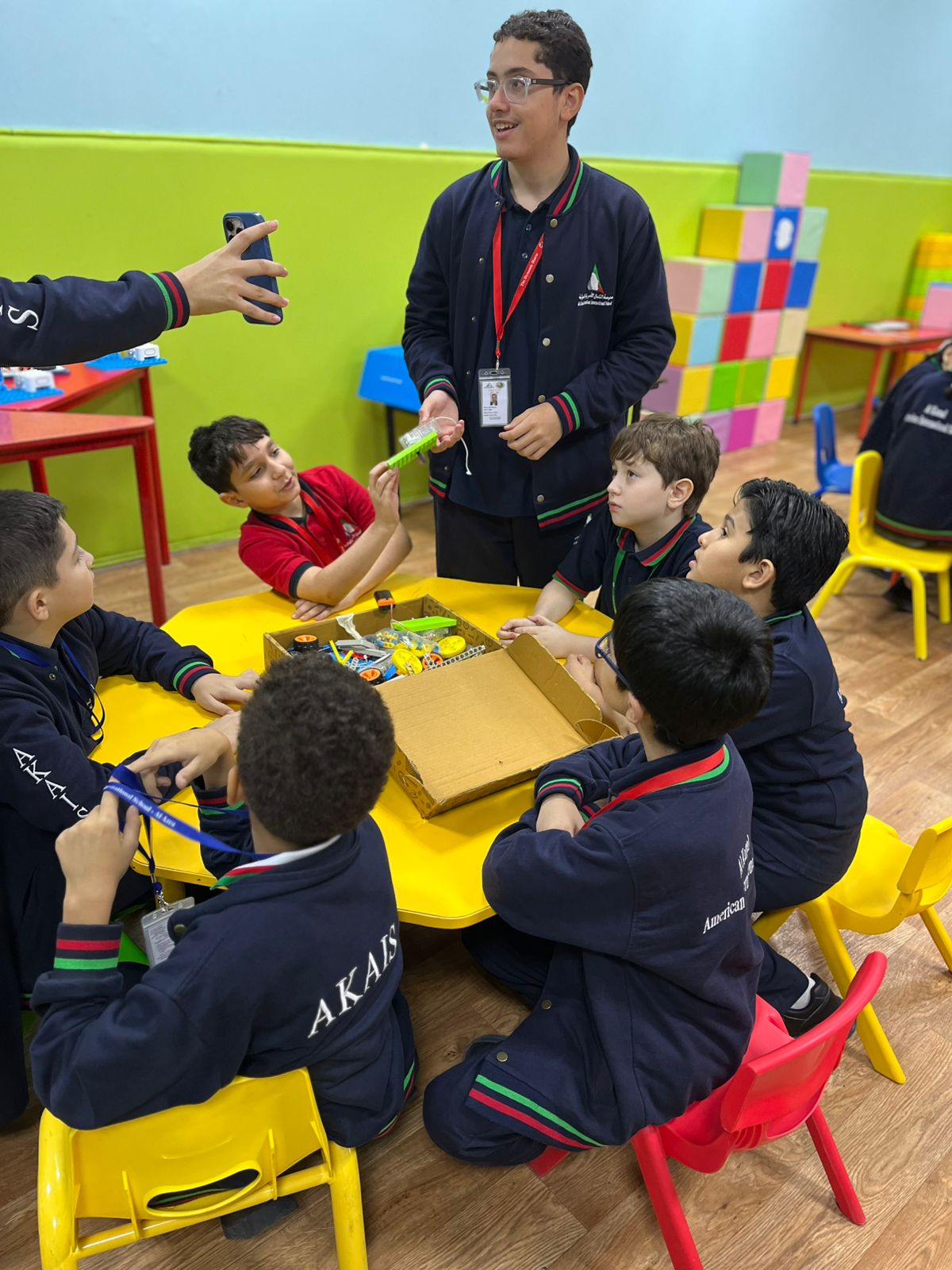 Students building models from construction components around a shared makerspace table in a UAE school
