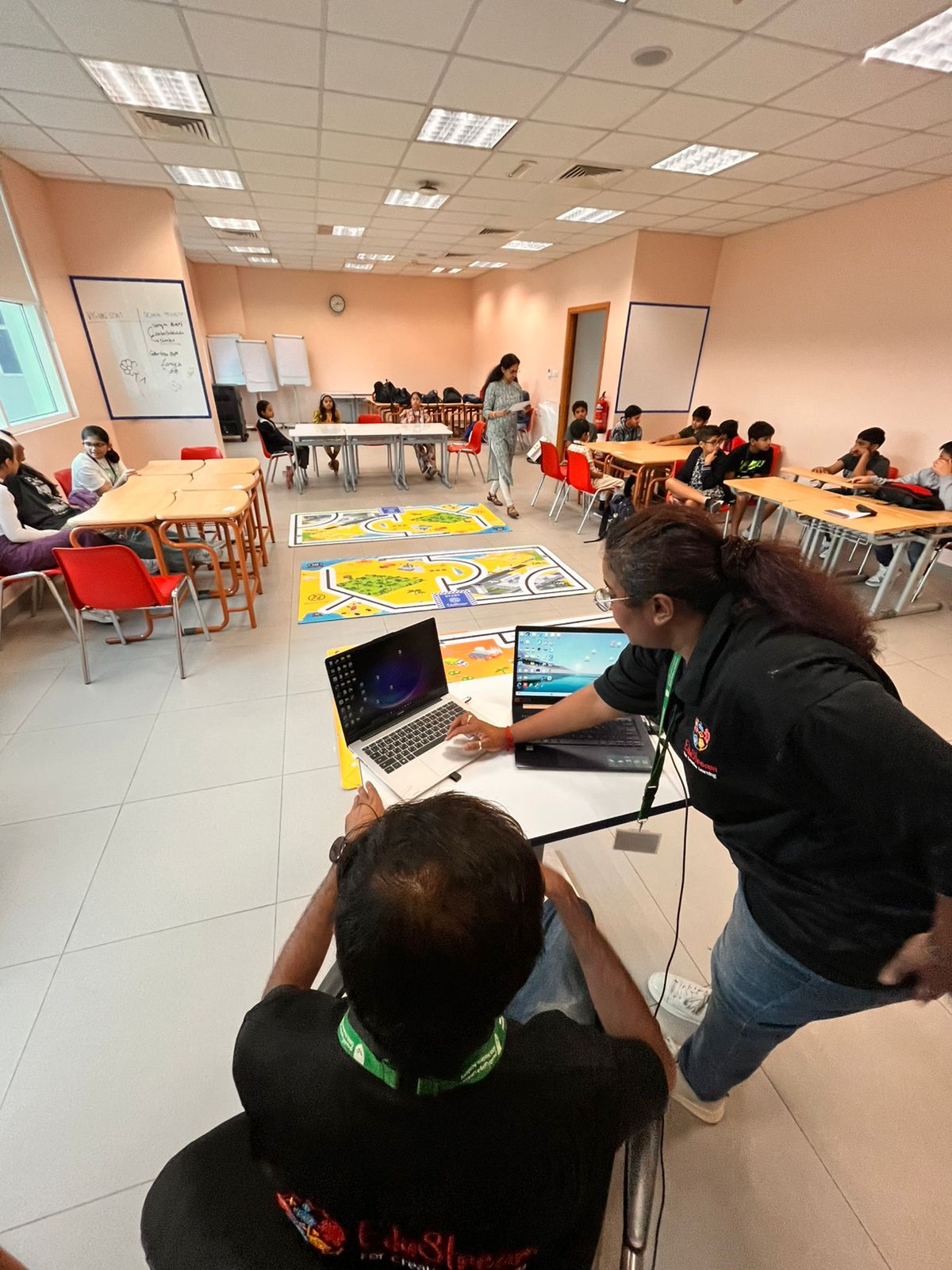 An EduStream facilitator guiding students at a laptop during a robotics activity in a UAE school