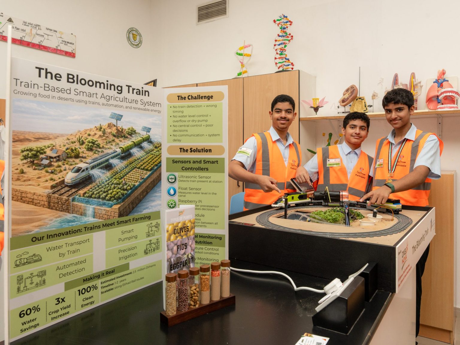 Three students in high-visibility vests beside their Blooming Train smart agriculture project display at the STEAM Champions UAE Nationals