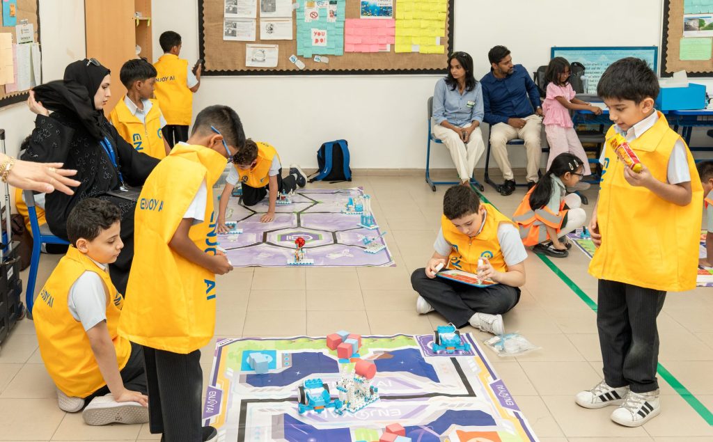 Students in team vests working with robots on a competition mat in a classroom at the STEAM Champions UAE Nationals