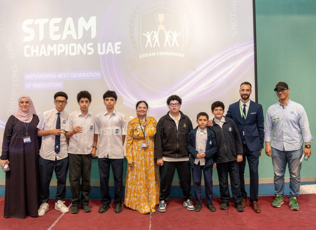 Students and adults standing on stage in front of a STEAM Champions UAE screen