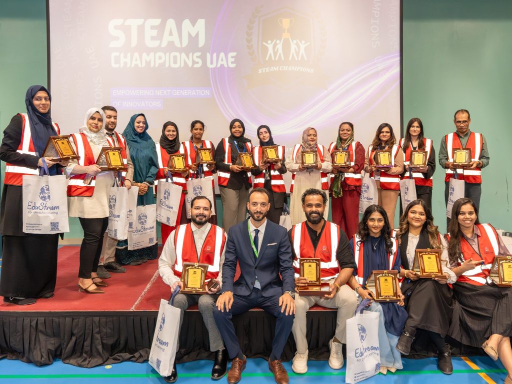 Group of adults in event vests holding plaques on stage in front of a STEAM Champions UAE screen